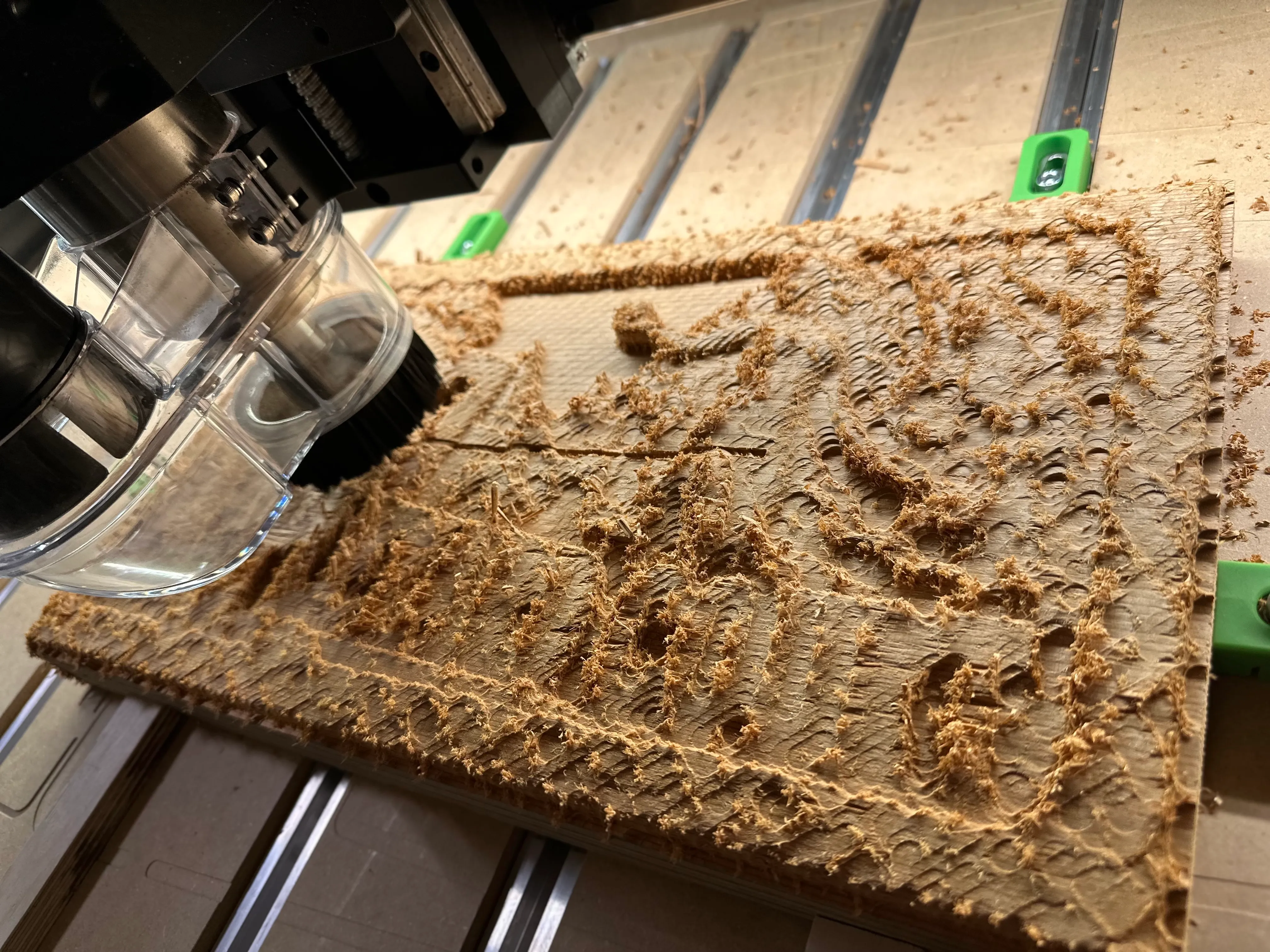 CNC router roughing out a cedar board, covered in wood chips